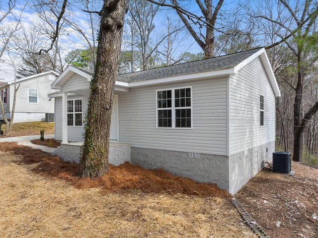 view of side of home featuring cooling unit and a shingled roof