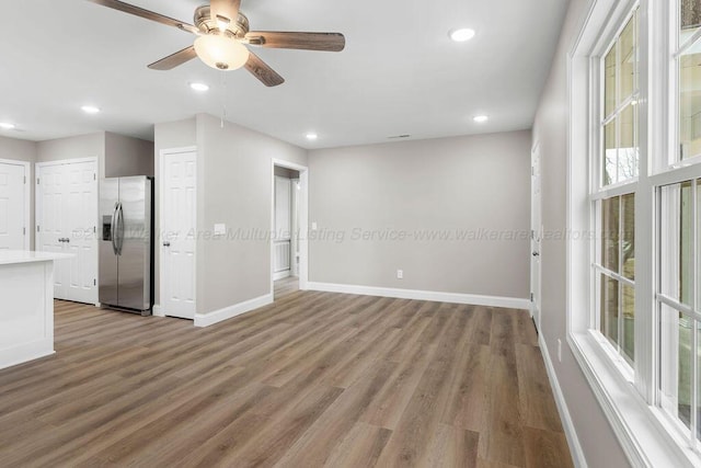 empty room featuring wood finished floors, baseboards, and recessed lighting