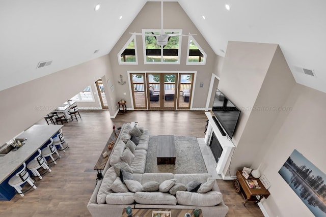 living room with a tiled fireplace, high vaulted ceiling, and hardwood / wood-style flooring