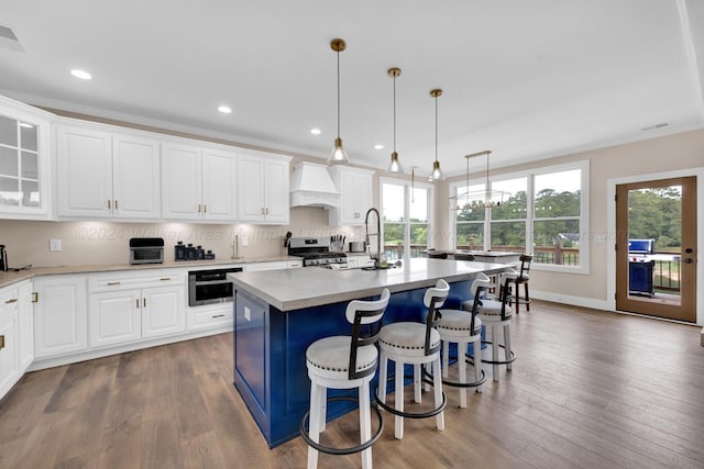 kitchen featuring dark hardwood / wood-style flooring, a center island with sink, hanging light fixtures, and appliances with stainless steel finishes