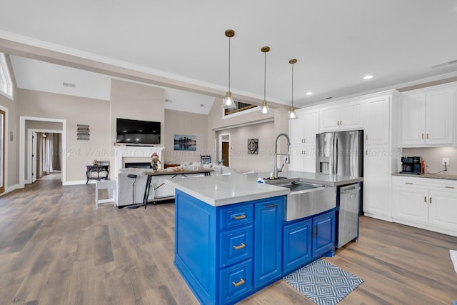 kitchen with sink, blue cabinets, a kitchen island with sink, white cabinets, and appliances with stainless steel finishes