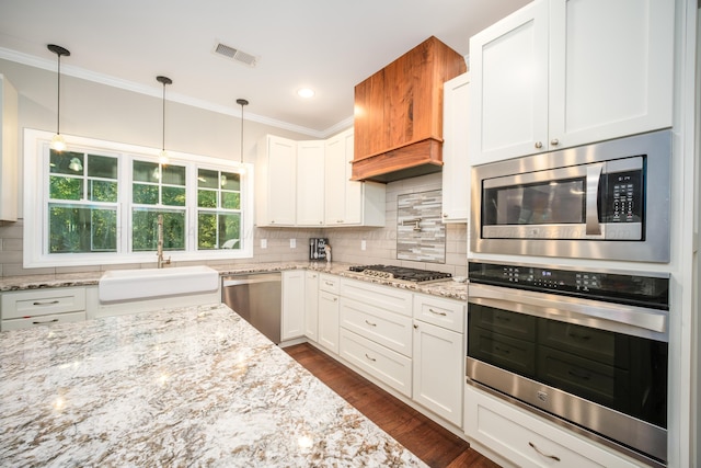 kitchen with visible vents, ornamental molding, decorative backsplash, appliances with stainless steel finishes, and a sink