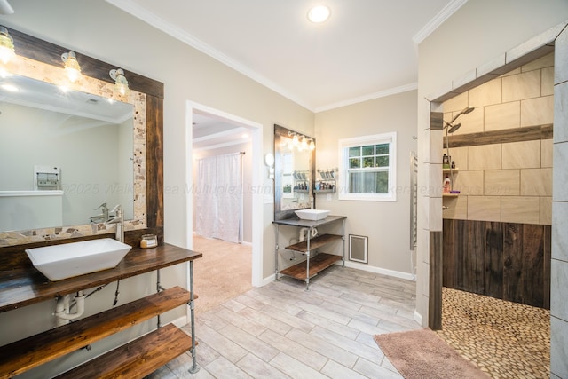 full bath featuring crown molding, baseboards, a tile shower, and a sink