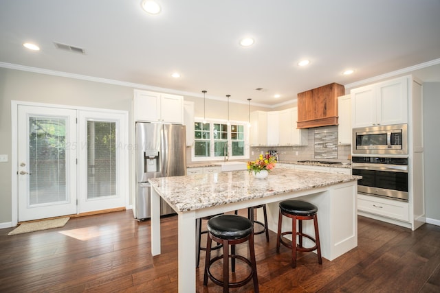 kitchen featuring backsplash, appliances with stainless steel finishes, ornamental molding, and dark wood finished floors