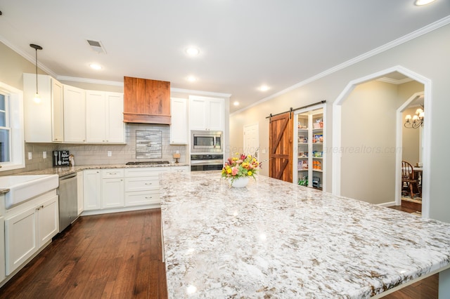 kitchen featuring a barn door, white cabinets, dark wood-style floors, and stainless steel appliances