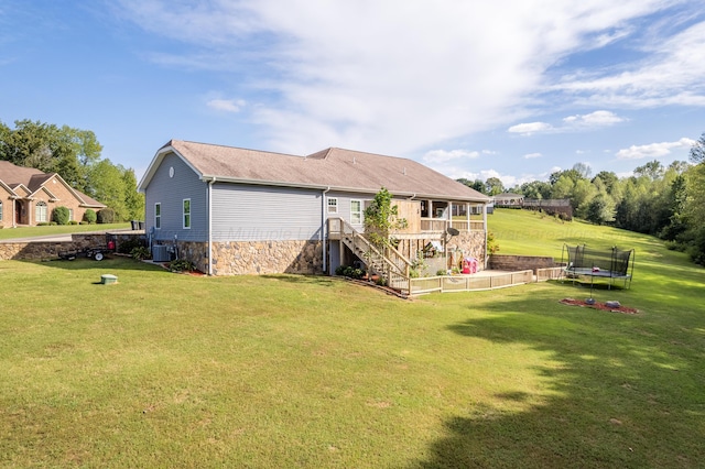 rear view of property with a trampoline, stairway, central AC, a yard, and stone siding