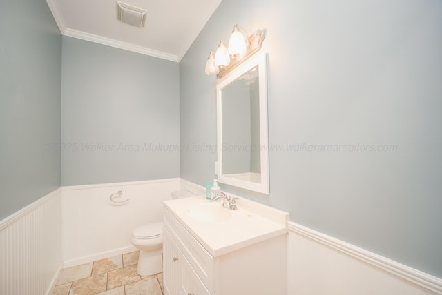 half bathroom featuring vanity, visible vents, ornamental molding, wainscoting, and toilet