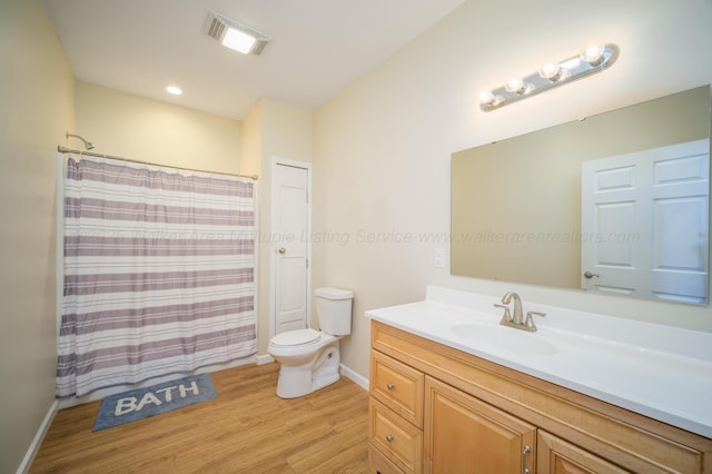 full bath featuring vanity, wood finished floors, visible vents, baseboards, and toilet