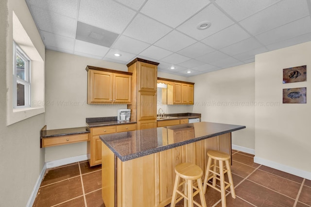 kitchen featuring a paneled ceiling, dark tile patterned floors, and sink