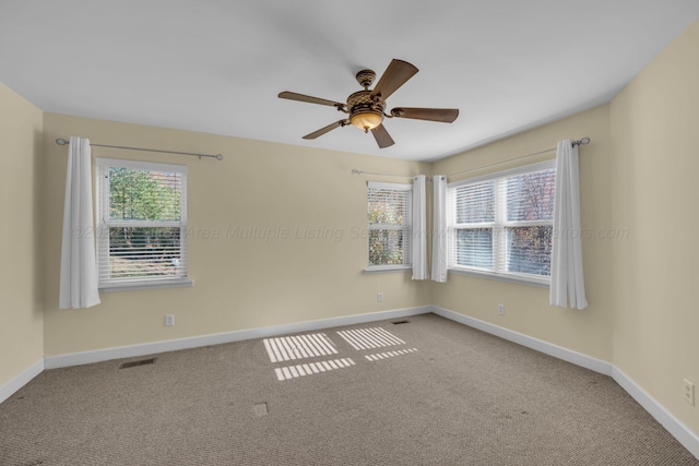 carpeted empty room featuring a wealth of natural light and ceiling fan