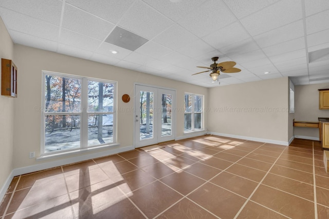 unfurnished living room featuring a paneled ceiling, tile patterned floors, and ceiling fan