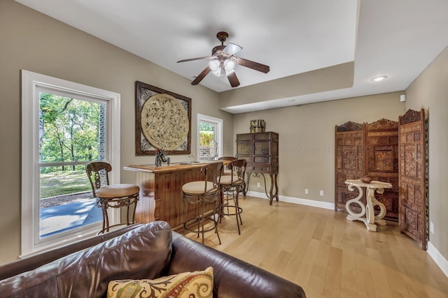 bar featuring ceiling fan and light hardwood / wood-style flooring