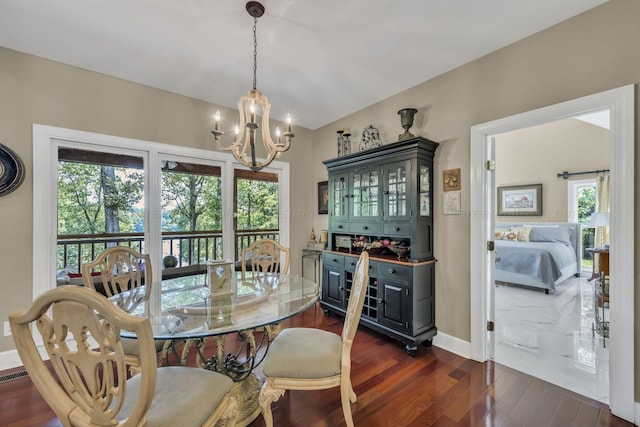 dining space featuring dark wood-type flooring, a healthy amount of sunlight, and a notable chandelier