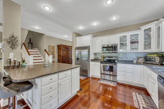 kitchen featuring white cabinets, a kitchen breakfast bar, dark hardwood / wood-style floors, and stainless steel appliances