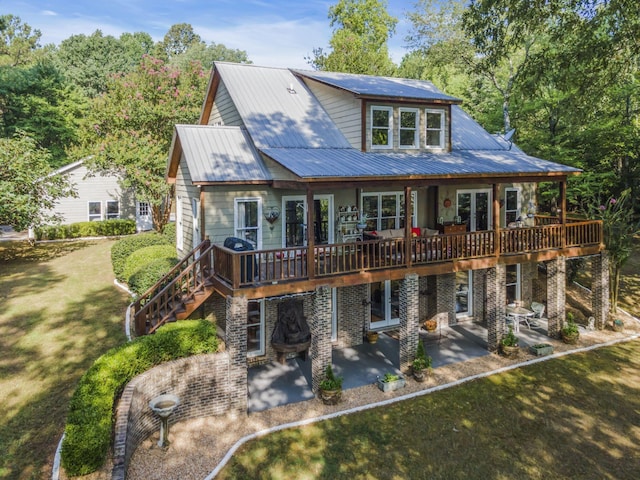 back of property featuring a wooden deck, a patio area, and a lawn