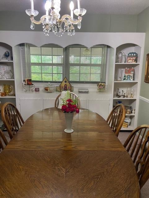 dining area with built in shelves, a textured ceiling, and an inviting chandelier