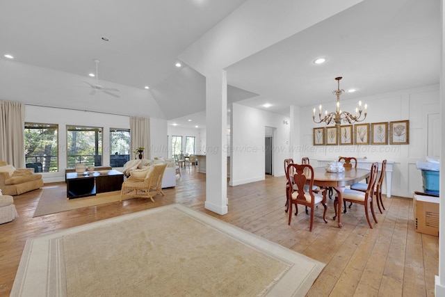 dining space featuring ceiling fan with notable chandelier, light hardwood / wood-style floors, and high vaulted ceiling