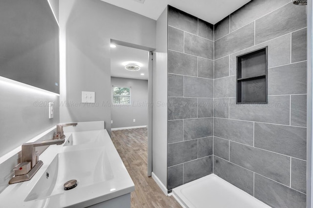 bathroom featuring a tile shower, vanity, and hardwood / wood-style flooring