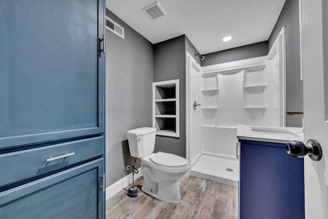 bathroom featuring wood-type flooring, vanity, toilet, and walk in shower