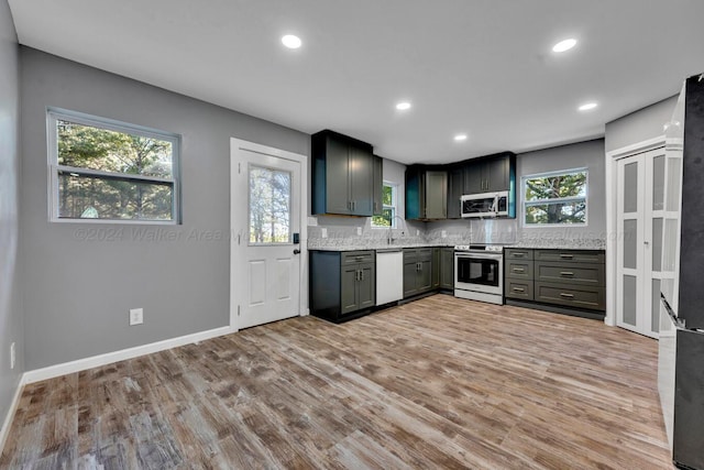 kitchen featuring appliances with stainless steel finishes, light hardwood / wood-style floors, plenty of natural light, and sink