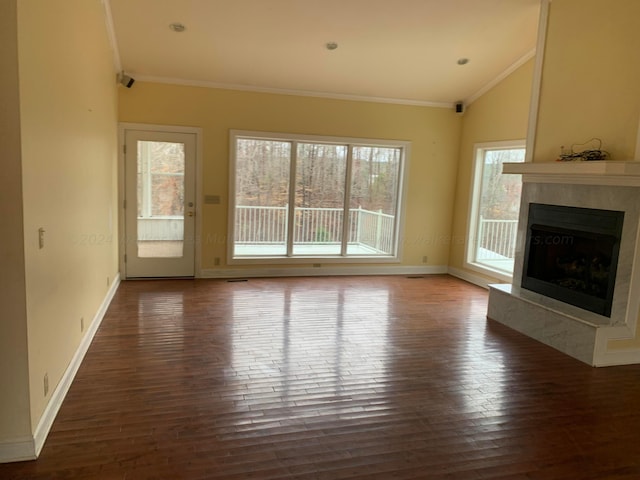 unfurnished living room with lofted ceiling, crown molding, plenty of natural light, and dark hardwood / wood-style floors