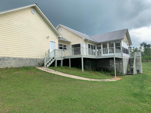 rear view of house featuring a sunroom, a deck, and a lawn