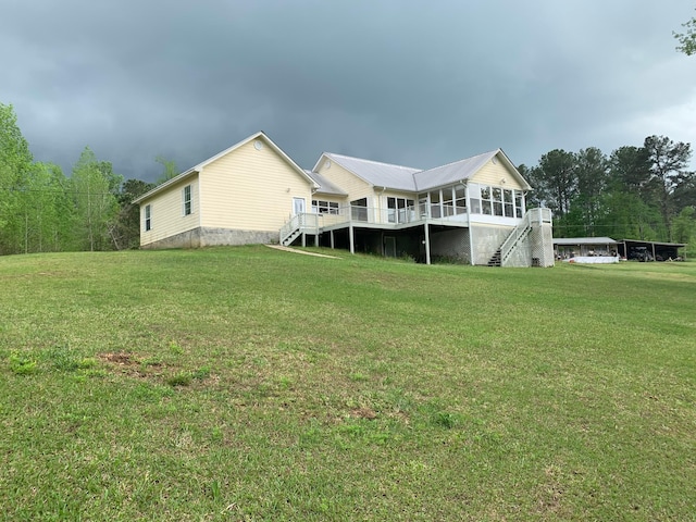 rear view of property featuring a yard and a sunroom