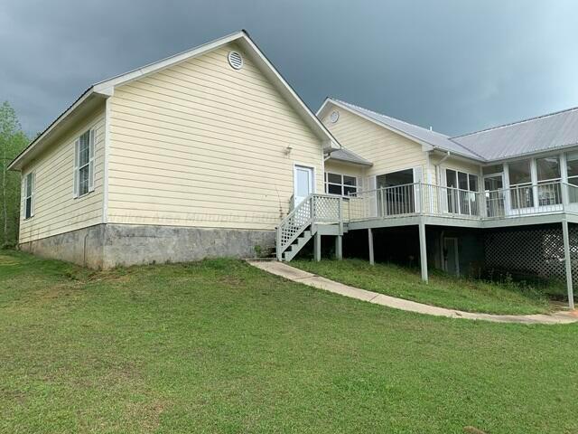 back of property featuring a lawn, a wooden deck, and a sunroom