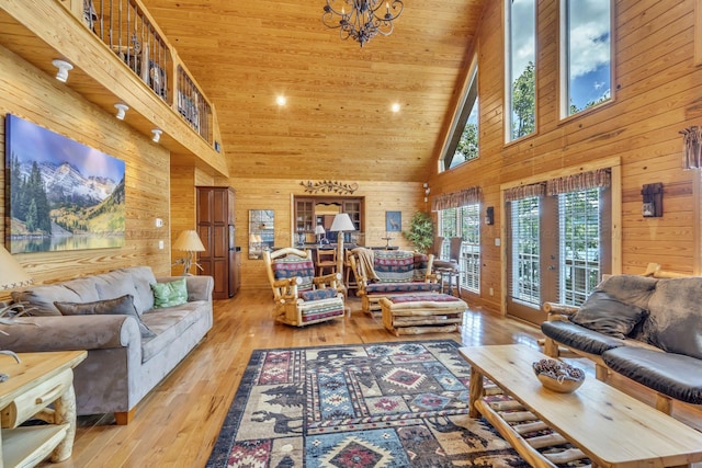 living room with wood ceiling, wood walls, high vaulted ceiling, and light hardwood / wood-style floors