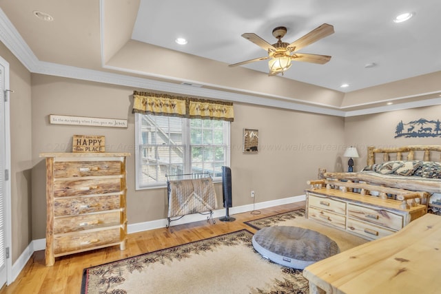 bedroom with hardwood / wood-style flooring, a raised ceiling, and ceiling fan