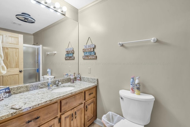 bathroom featuring vanity, toilet, ornamental molding, and a shower with door