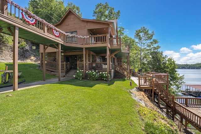 back of property featuring a deck with water view and a lawn