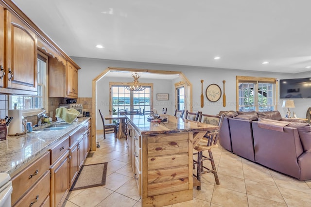 kitchen featuring a notable chandelier, a kitchen bar, a wealth of natural light, and tasteful backsplash