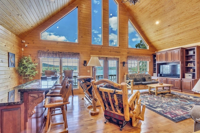 living room featuring wood walls, high vaulted ceiling, and light hardwood / wood-style floors