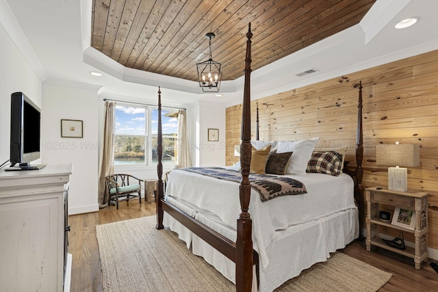 bedroom with wood walls, a chandelier, light hardwood / wood-style floors, a tray ceiling, and wood ceiling