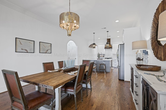 dining area with dark hardwood / wood-style floors, ornamental molding, and a notable chandelier