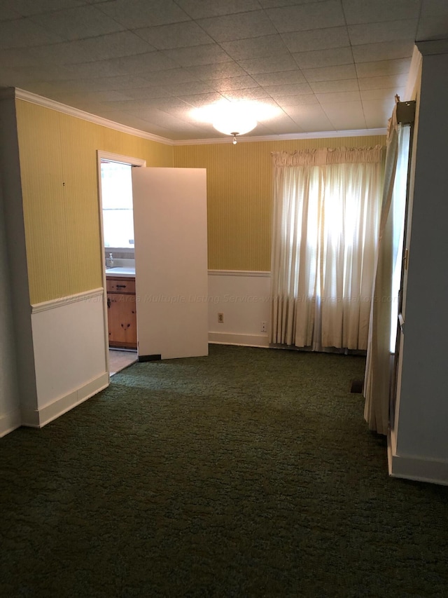 spare room with crown molding and dark carpet