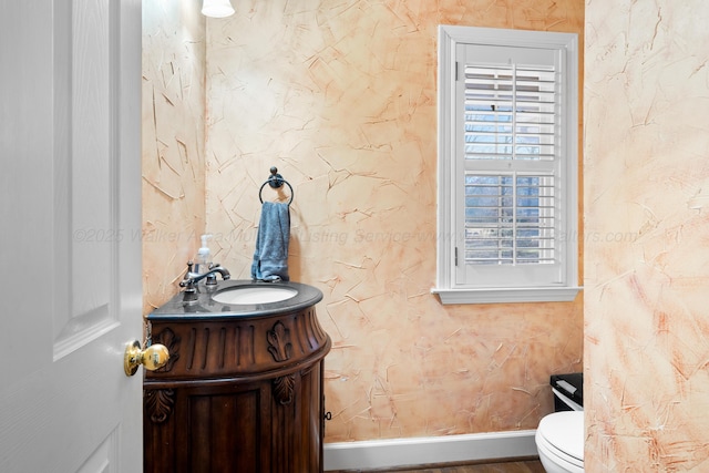 bathroom featuring toilet, vanity, and baseboards