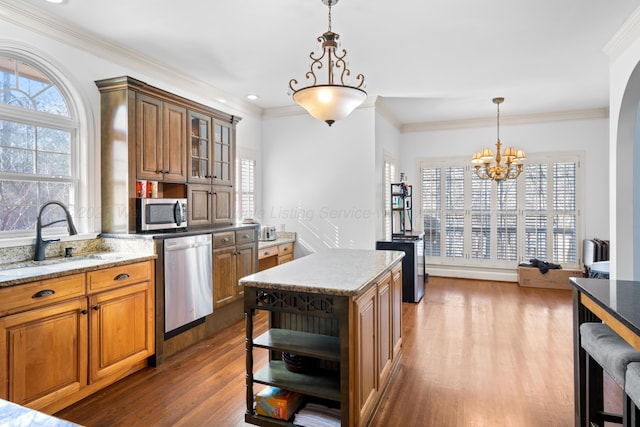 kitchen featuring appliances with stainless steel finishes, brown cabinetry, glass insert cabinets, and a sink