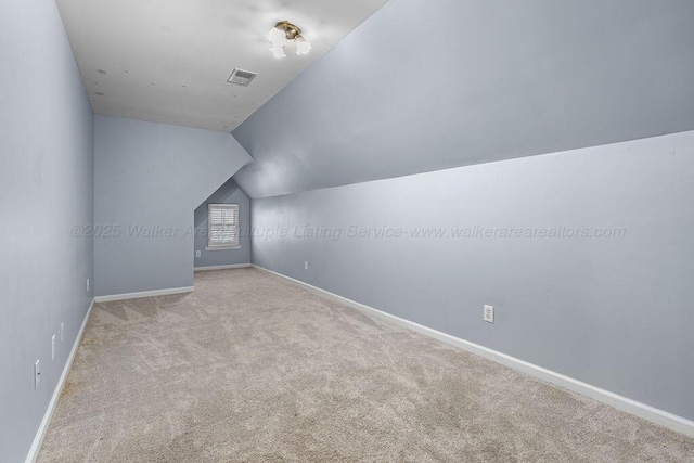 bonus room featuring light colored carpet, visible vents, lofted ceiling, and baseboards