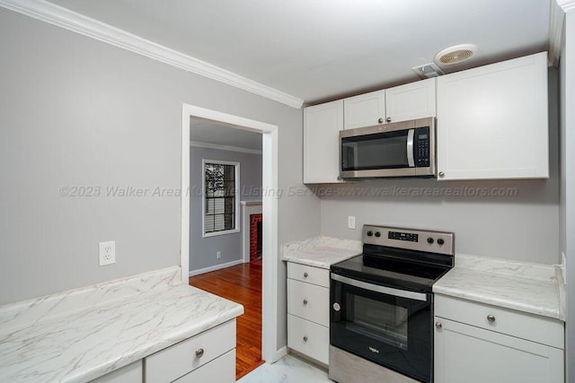 kitchen with appliances with stainless steel finishes, crown molding, white cabinetry, and light stone counters