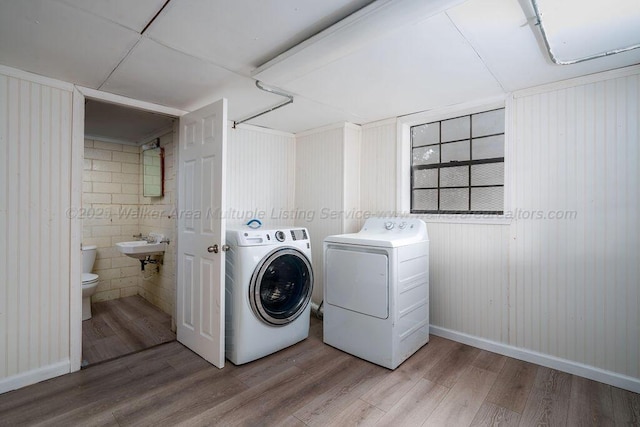 laundry room featuring sink, independent washer and dryer, and light hardwood / wood-style flooring