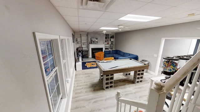 playroom featuring billiards, a ceiling fan, wood finished floors, a paneled ceiling, and a fireplace