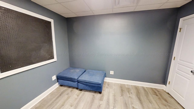 living area with light wood-type flooring, baseboards, and a drop ceiling