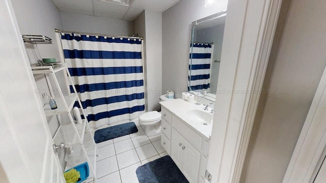 bathroom with toilet, a paneled ceiling, tile patterned flooring, and vanity