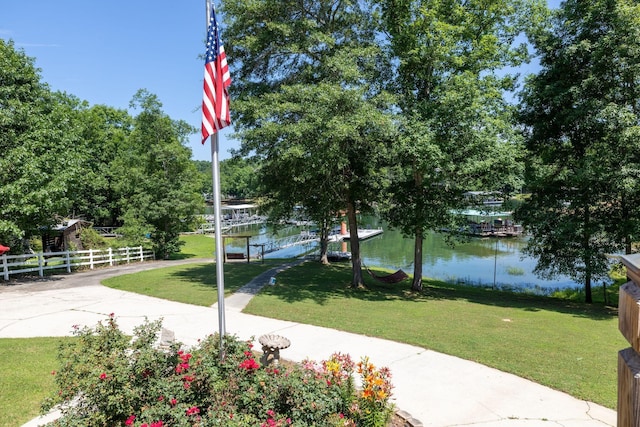 view of home's community with a boat dock, a yard, and a water view