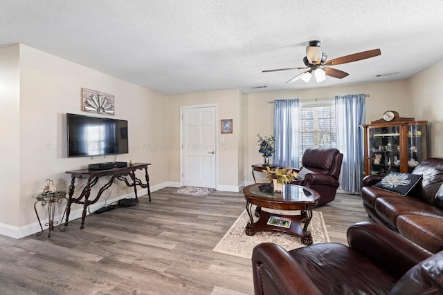 living room with a textured ceiling, hardwood / wood-style flooring, and ceiling fan