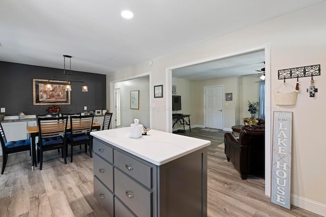 kitchen with ceiling fan, gray cabinets, a center island, light hardwood / wood-style floors, and hanging light fixtures