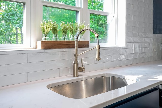 interior details with light stone counters, sink, and backsplash