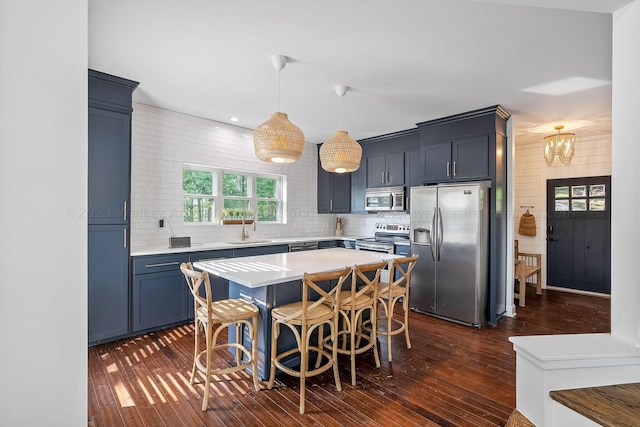 kitchen featuring a breakfast bar, decorative light fixtures, sink, stainless steel appliances, and blue cabinetry